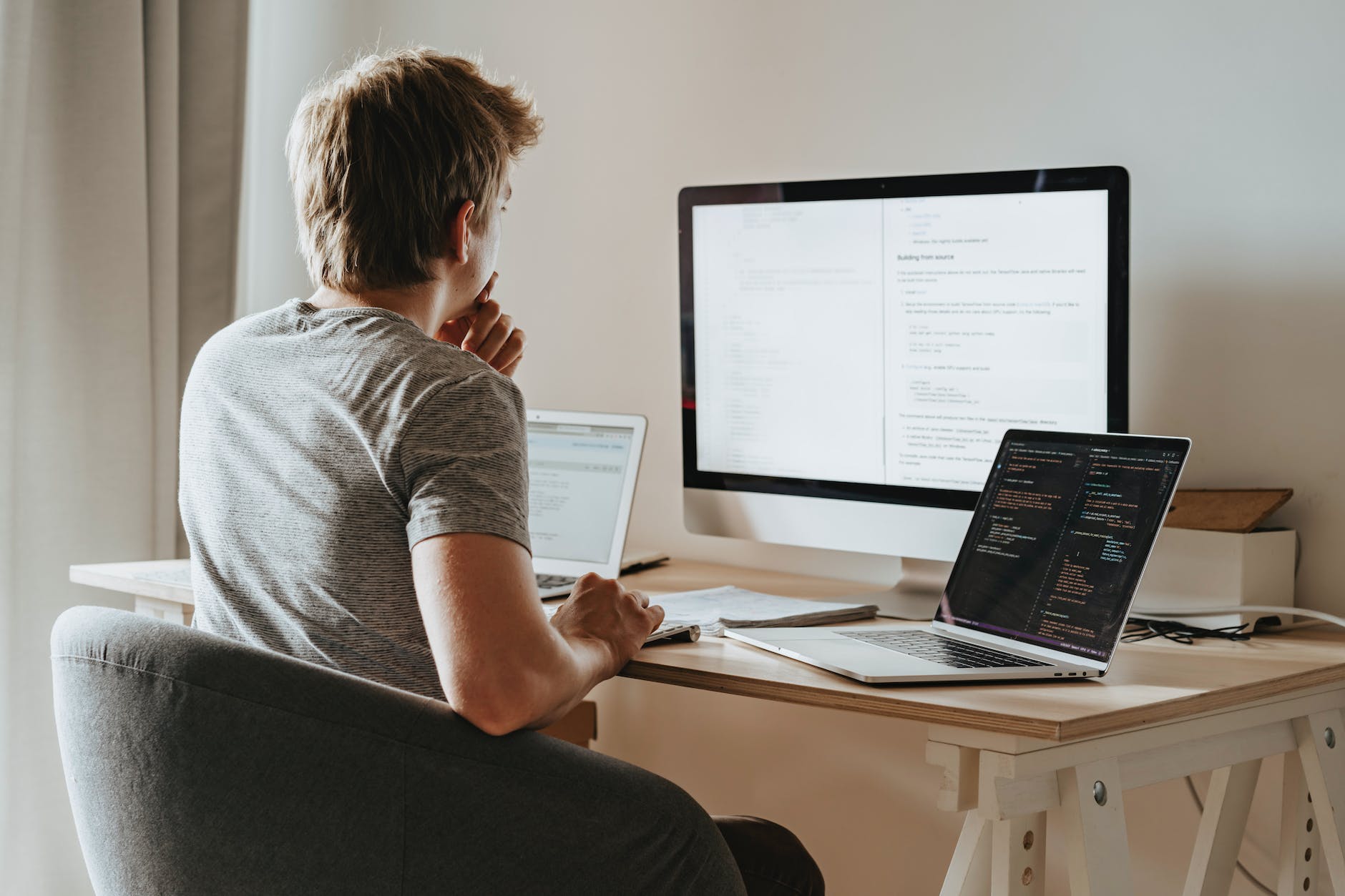 man sitting in front of three computers